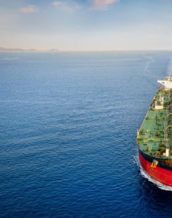 Aerial front view of a heavy crude oil tanker traveling over calm sea during sunset